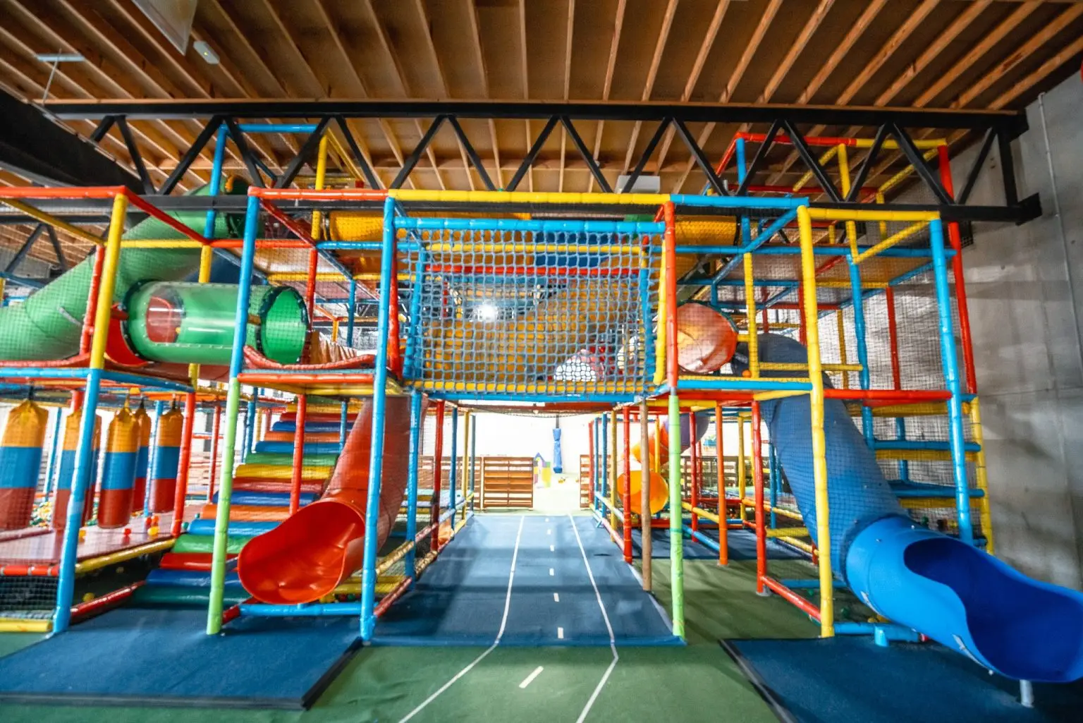 The downstairs playground at Kid???s Paradise: a multi-level climbing frame with tube slides, a ball pit and a rope net.